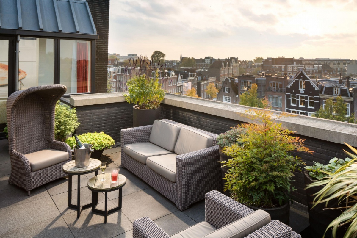 Andaz Amsterdam Prinsengracht - a patio with furniture and plants on the roof