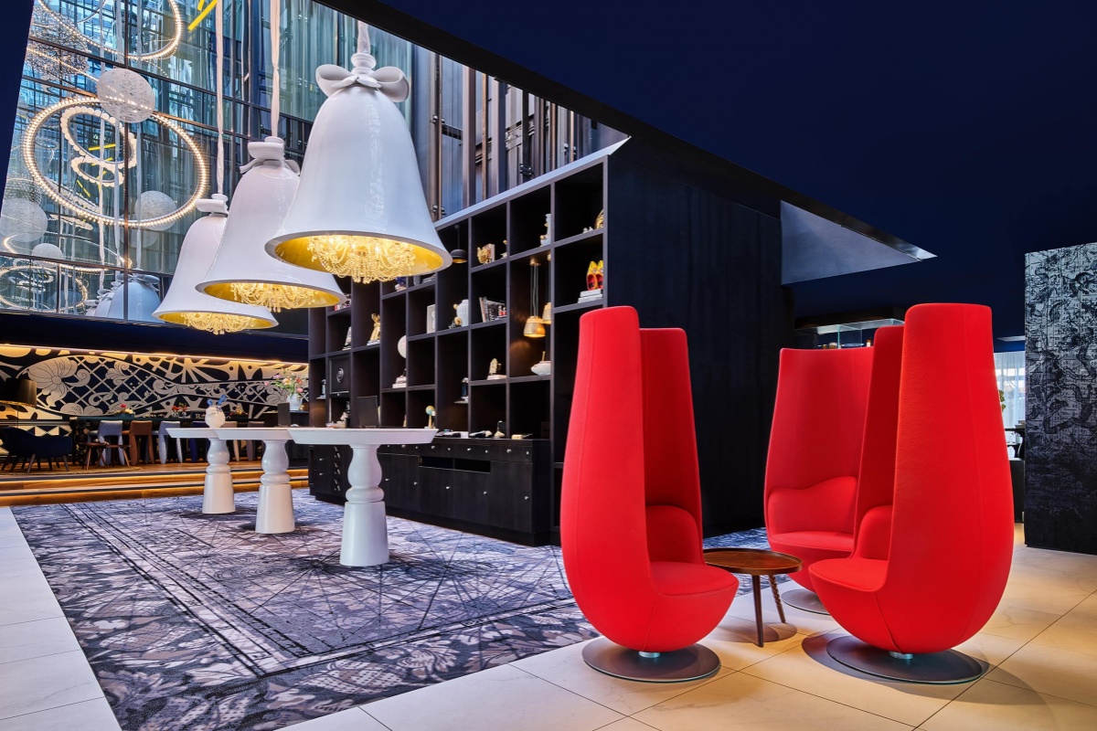 Andaz Amsterdam Prinsengracht - a room with red chairs and white lamps