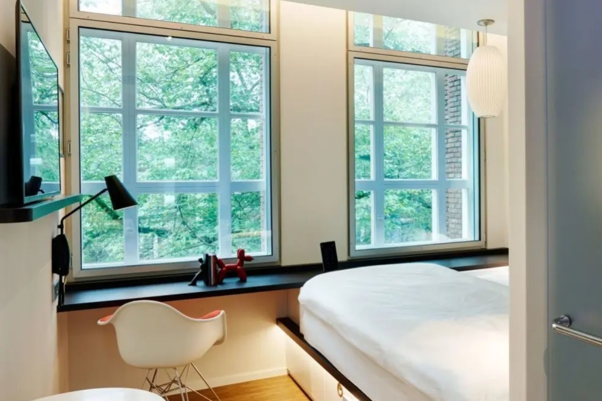 citizenM Amstel Amsterdam - a bedroom with a bed and chairs