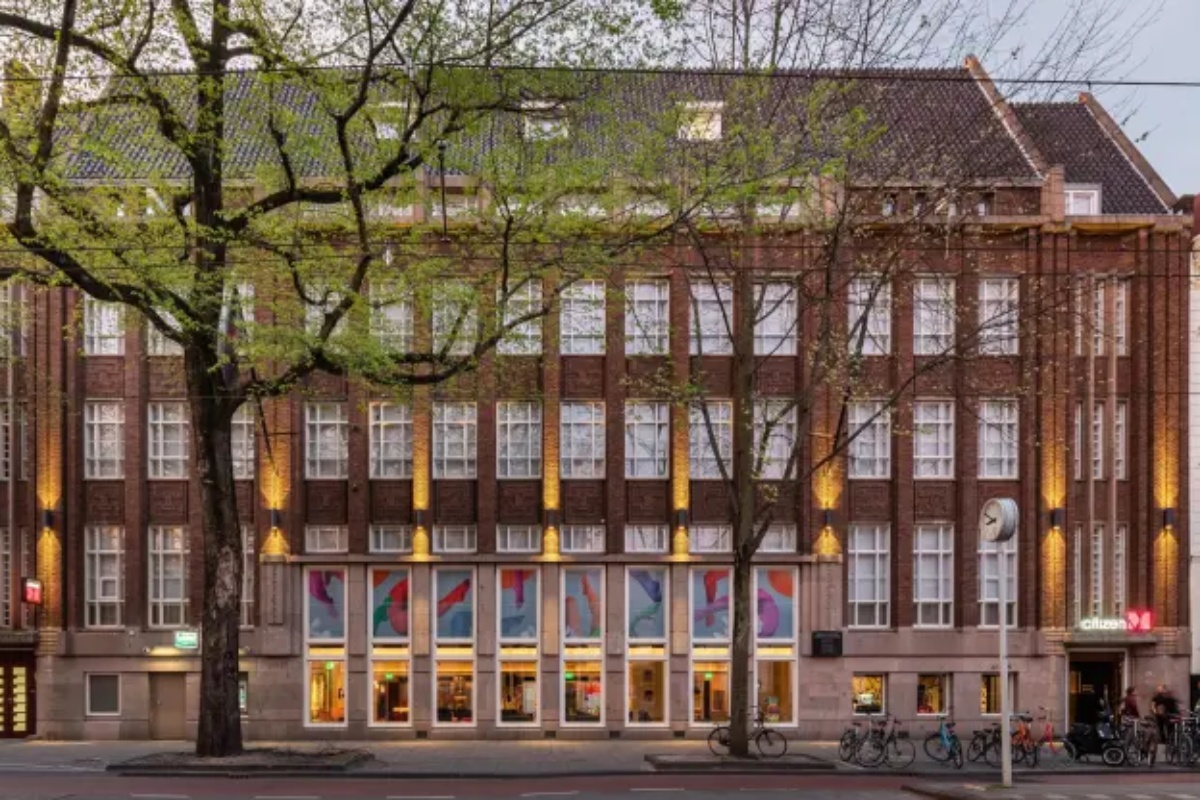 citizenM Amstel Amsterdam - a building with many windows and a street with trees