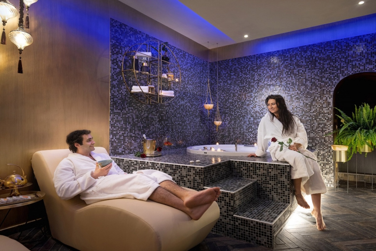 Dharma Boutique Hotel & Spa - A couple relaxing in the spa with a jacuzzi bath and mosaic tiled walls.