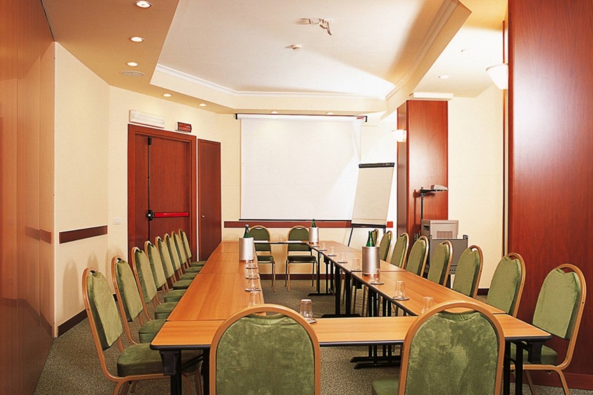 Hotel Colosseum - Conference room with a long table, chairs and flip chart.
