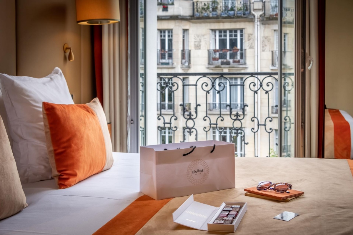 Hotel La Bourdonnais - a bed with a bag and a box of chocolates