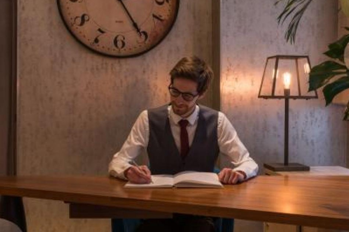 Hotel Le Walt - a man sitting at a desk writing on a book