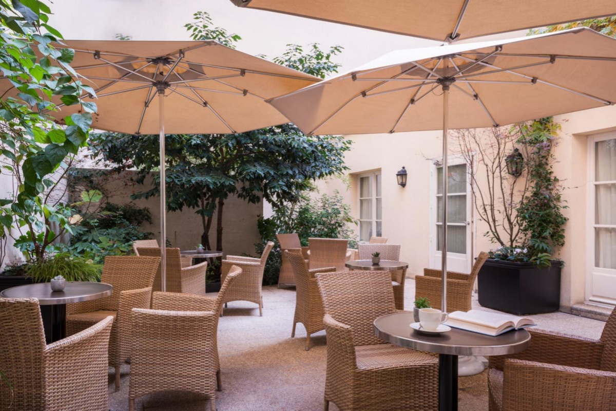 Hotel Le Walt - a patio with chairs and umbrellas