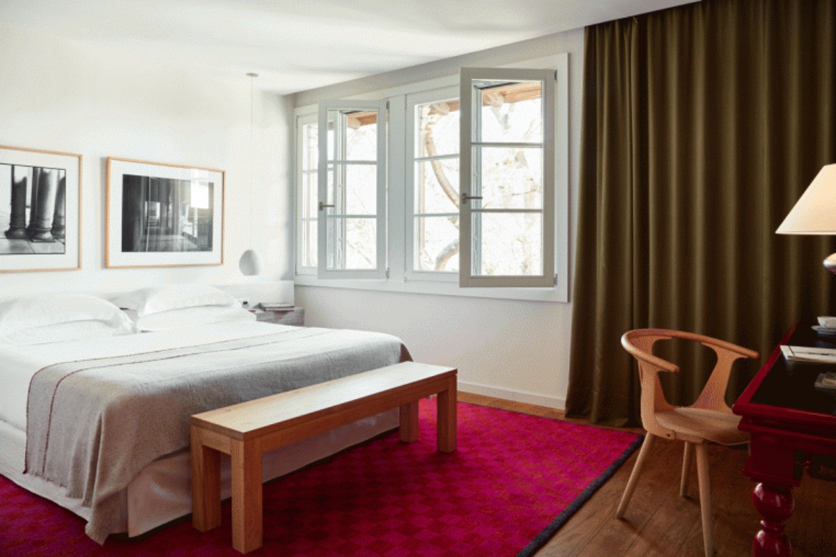 Hotel Neri Relais & Chateaux - a bedroom with a bed and a bench