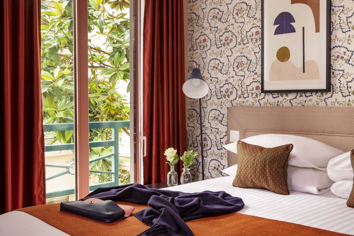 Hotel Relais Bosquet Paris by Malone - a bed with a blanket and a lamp next to a window