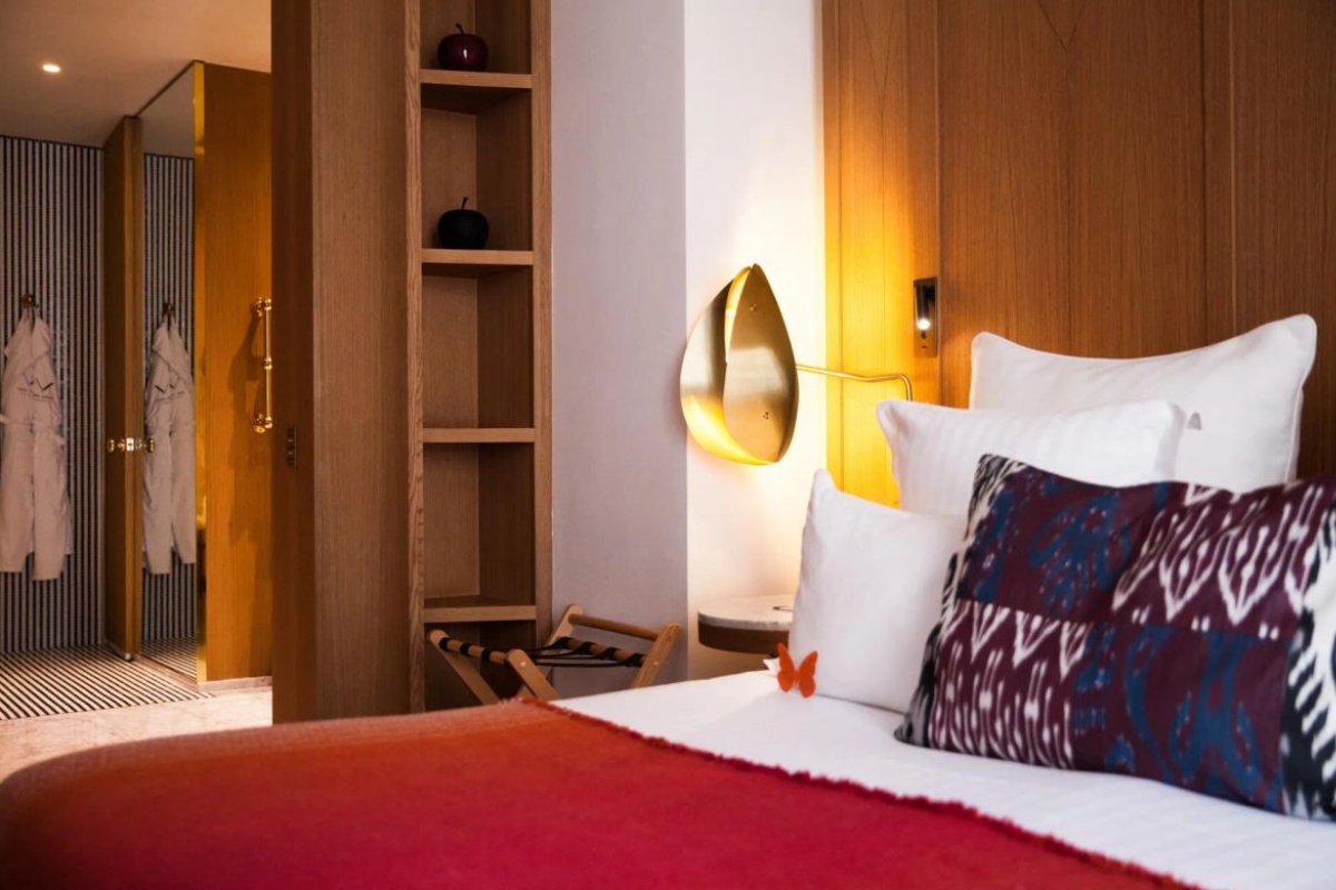 Hotel Vernet - a bed with pillows and a red blanket in a room