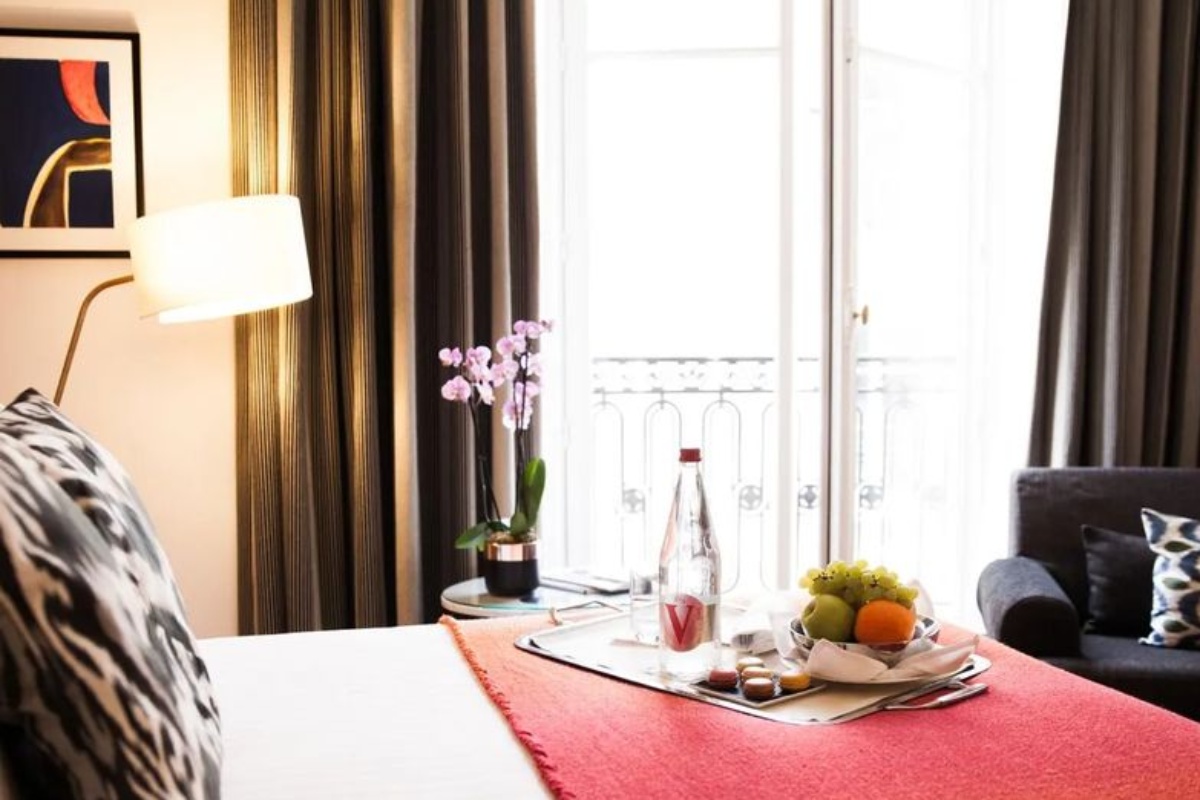 Hotel Vernet - a person sitting on a bed with a tray of food