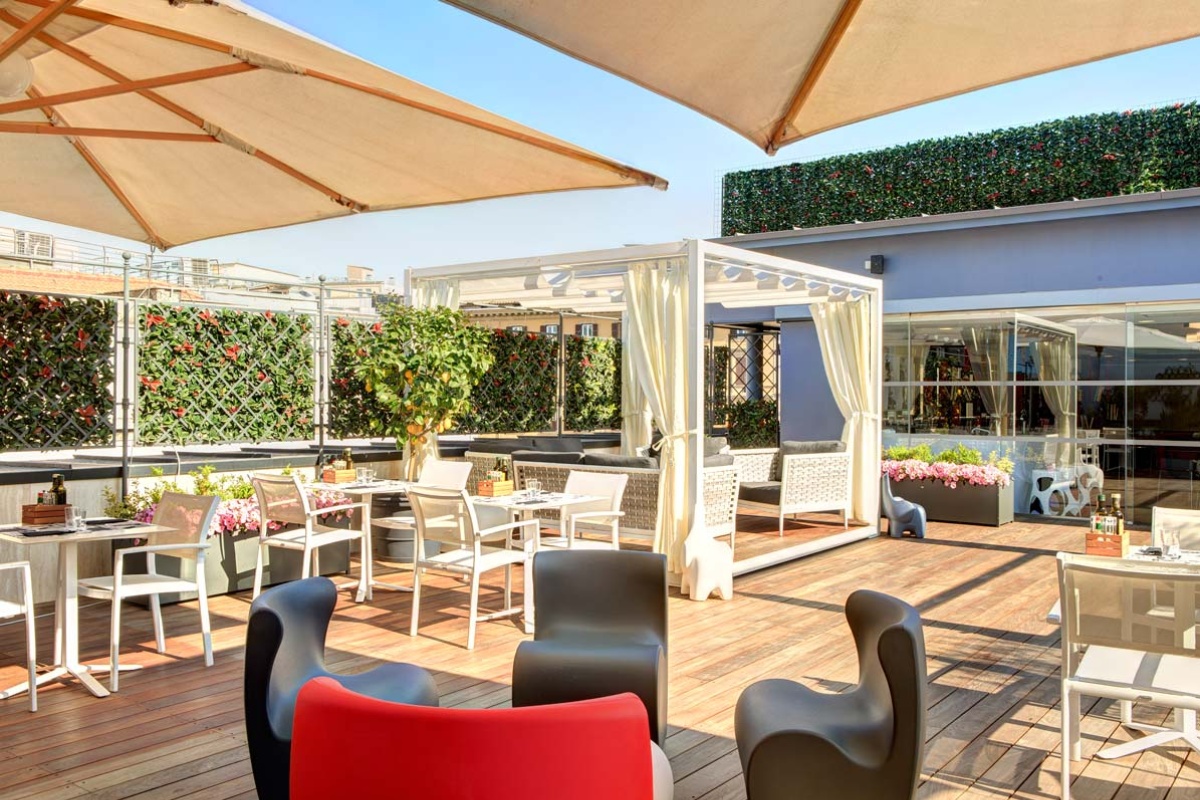 iQ Hotel Roma - Rooftop terrace with comfortable seating and shaded areas.