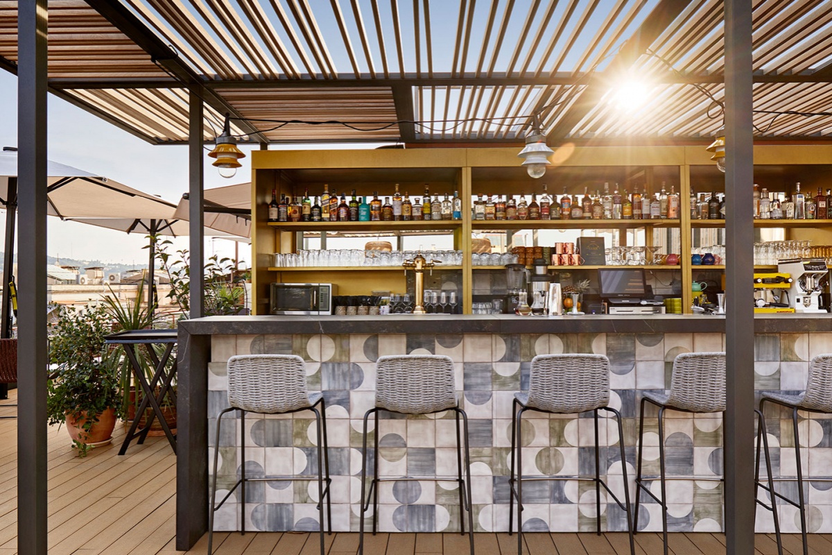 Kimpton Vividora Hotel - a bar with chairs and a table with a sun shining through