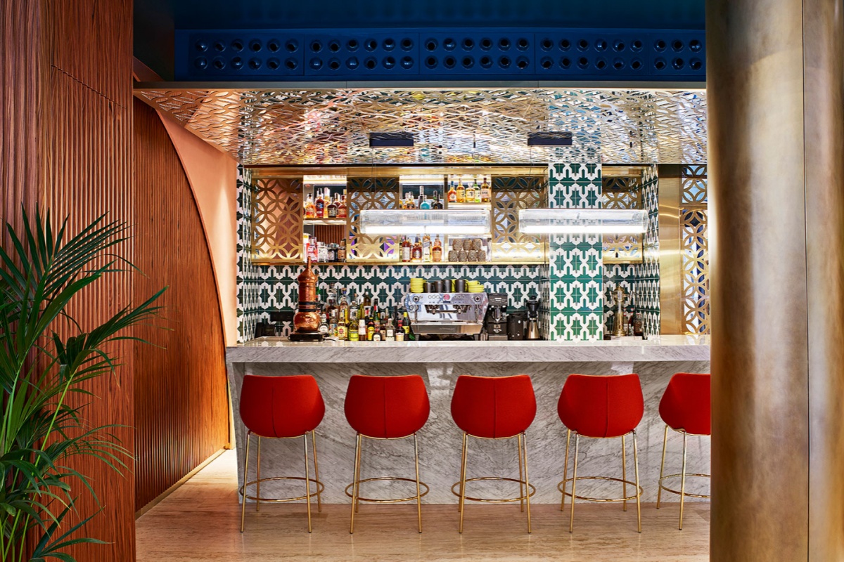 Kimpton Vividora Hotel - a bar with red chairs and a counter