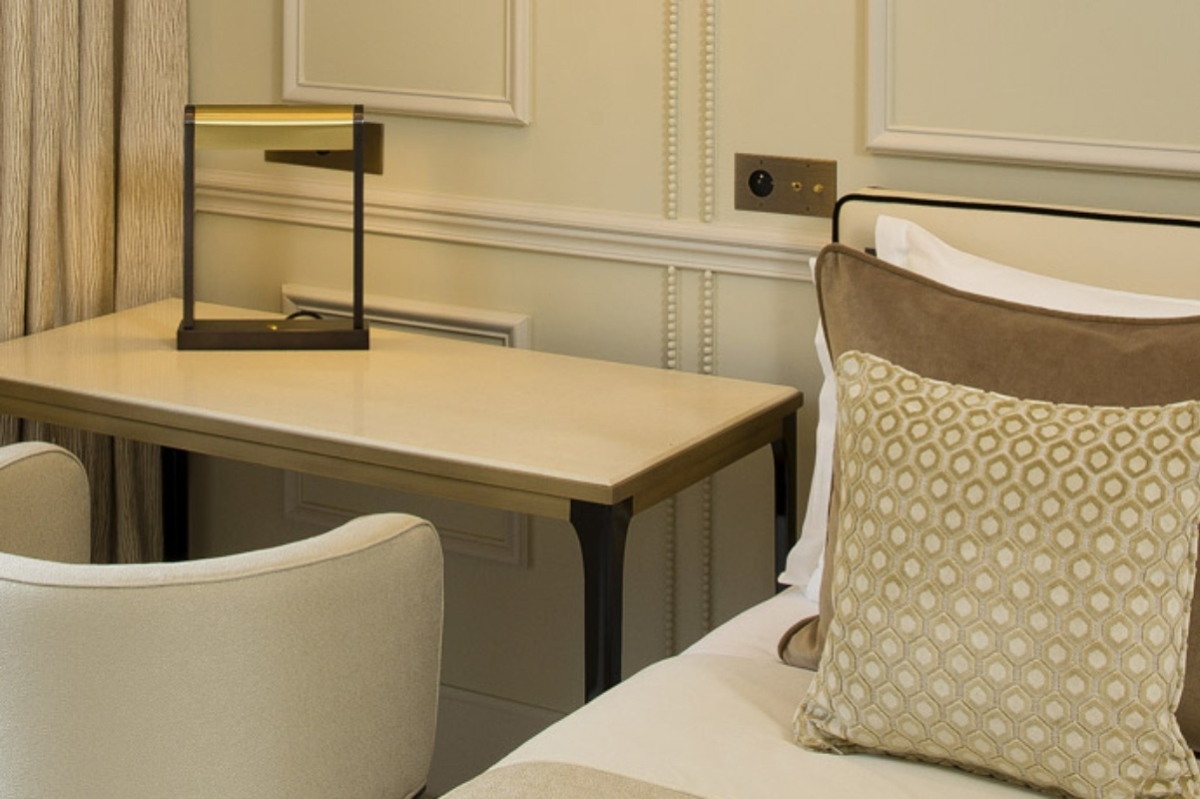 Le Narcisse Blanc Hotel & Spa - a bed with pillows and a desk