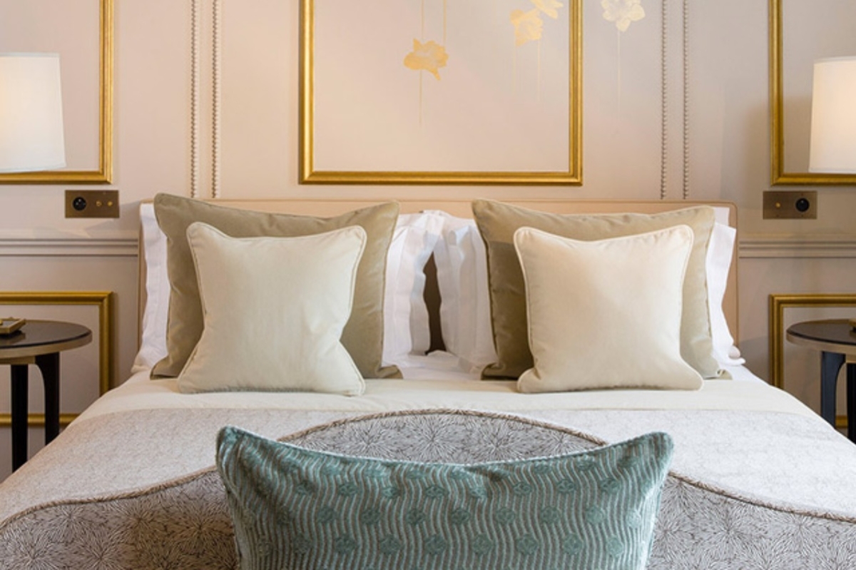Le Narcisse Blanc Hotel & Spa - a bed with pillows and a picture on the wall