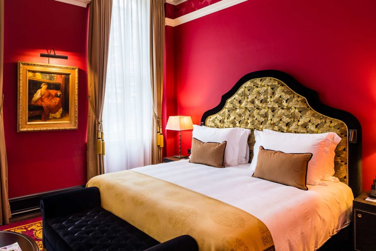 L'oscar London - a bed with a red wall and a lamp
