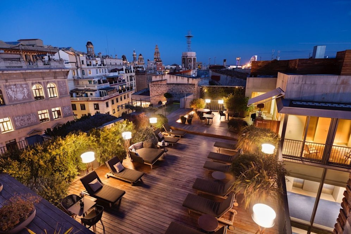 Mercer Hotel Barcelona - a rooftop patio with chairs and tables and lights