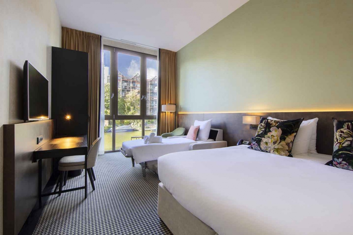 Monet Garden Hotel Amsterdam - a room with two beds and a black television