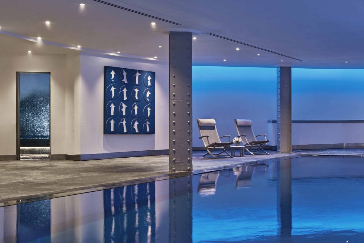 One Aldwych - a pool with chairs and a poster on the wall