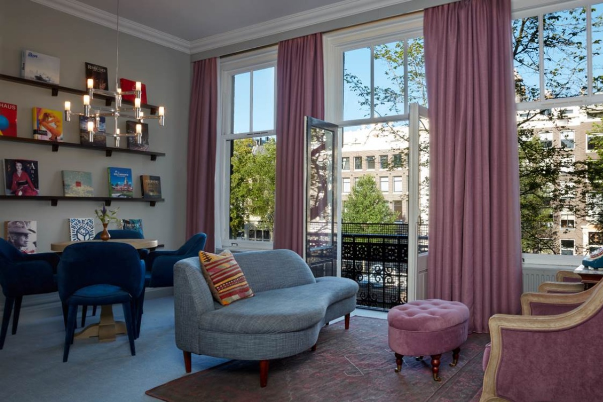 Pulitzer Amsterdam - a living room with pink curtains and a couch