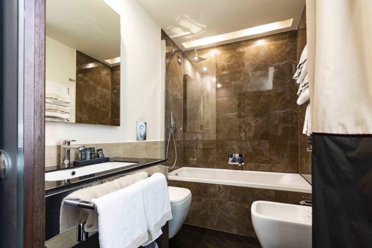 Rome Times Hotel - A modern bathroom with bathtub and overhead shower.