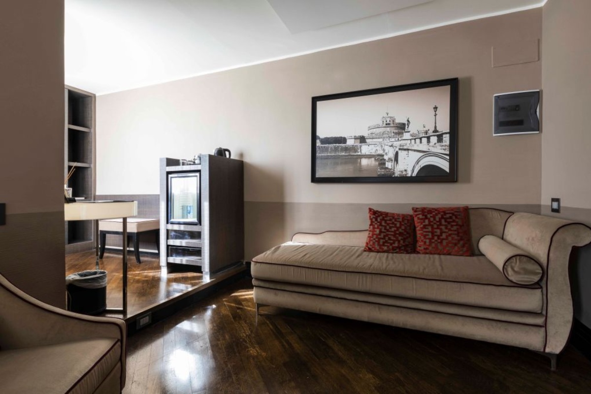 Rome Times Hotel - The lounge area of a bedroom with plush furnishings and wooden floor.