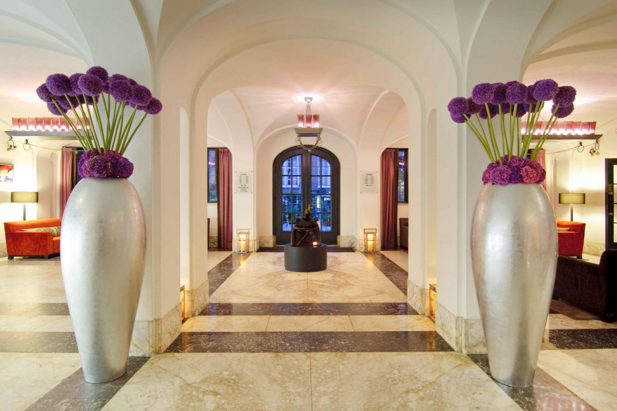 Sofitel Legend The Grand Amsterdam - a hallway with large vases of purple flowers