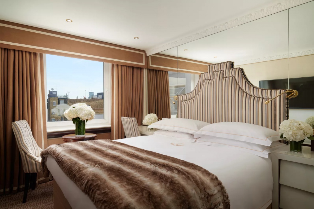 The Chesterfield Mayfair - a bed with a large mirror and a vase of flowers