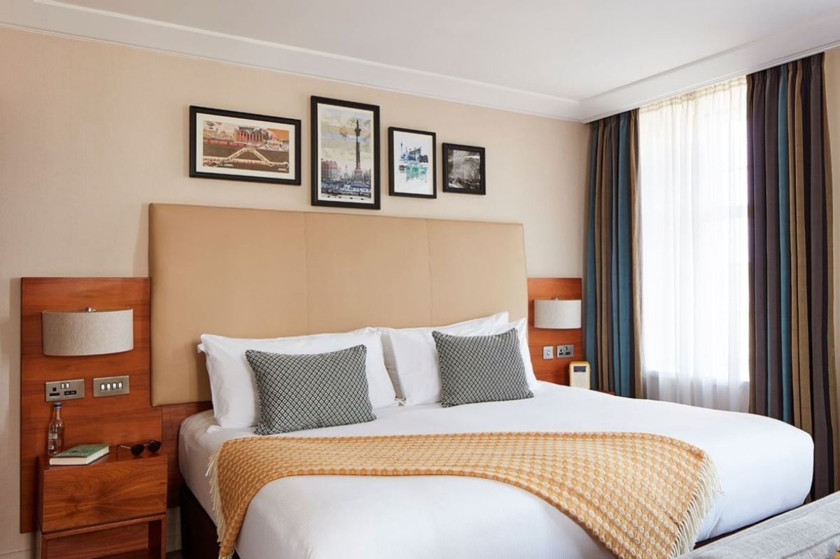 The Clermont, Charing Cross - a bed with pillows and a headboard in a hotel room