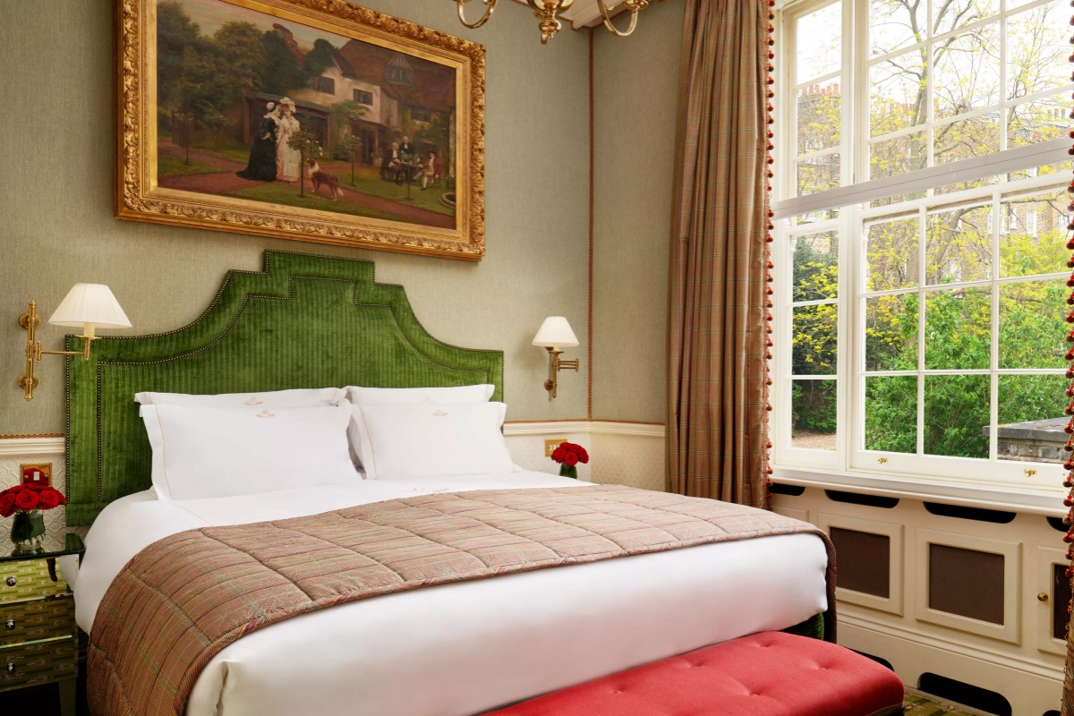The Montague on The Gardens - a bed with a green headboard and a red bench