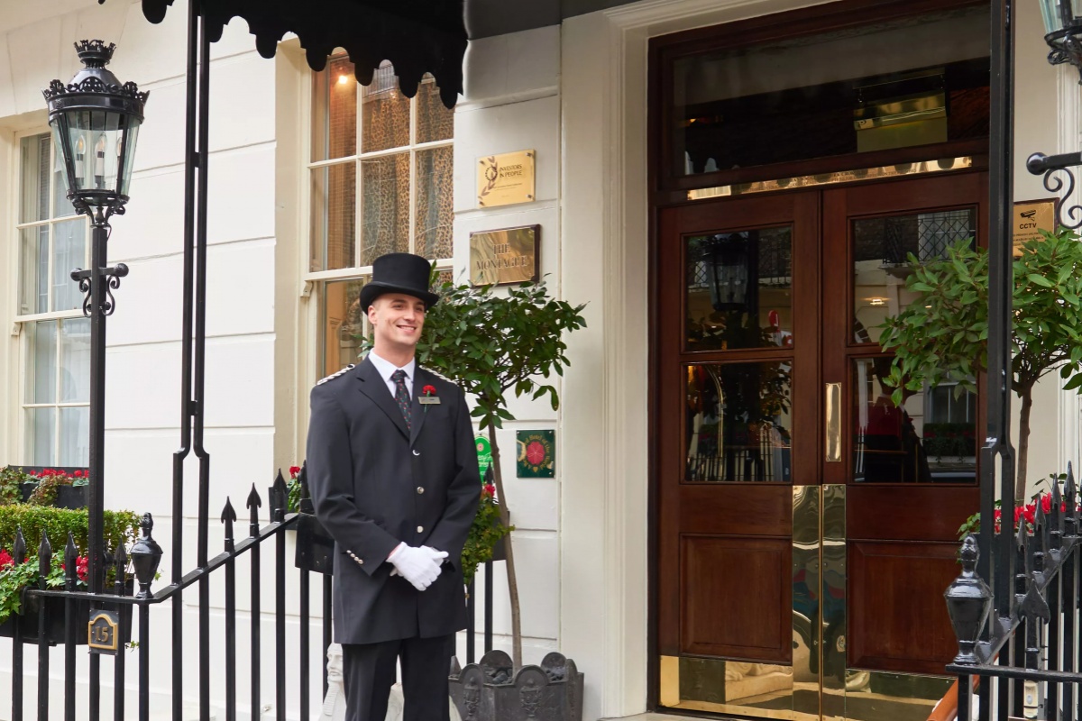 The Montague on The Gardens - a man in a suit and hat standing outside a building
