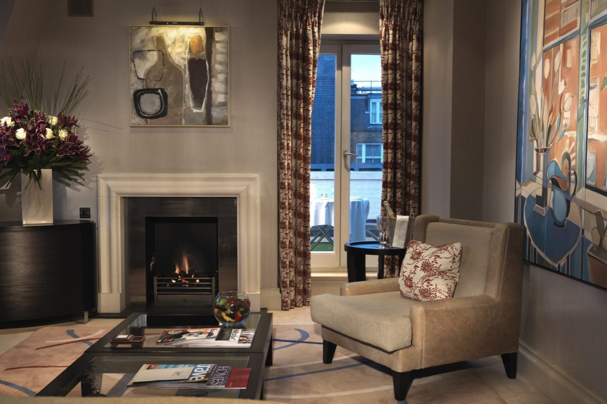 The Stafford London - a living room with a fireplace and a chair