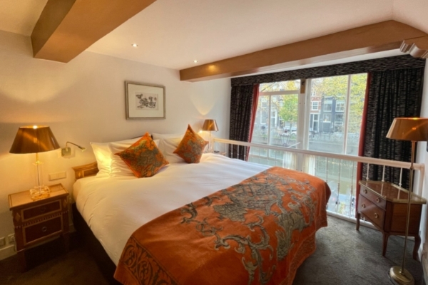 Ambassade Hotel - a bed with orange and grey pillows