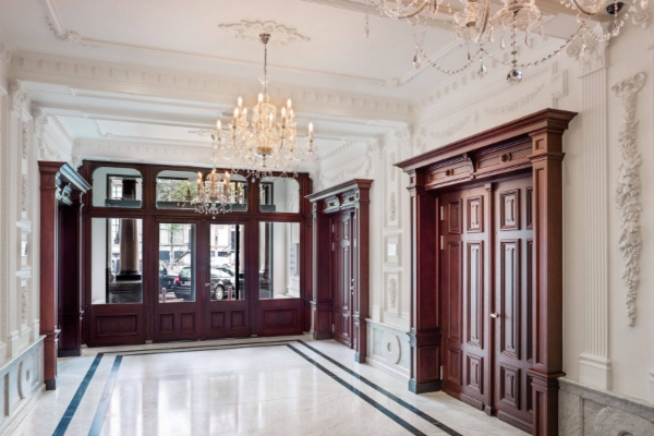 Andaz Amsterdam Prinsengracht - a room with wood doors and chandeliers