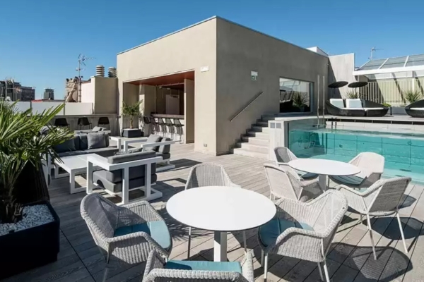 Catalonia Magdalenes - a patio with chairs and tables and a pool