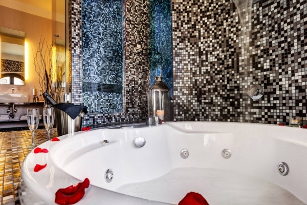 Dharma Luxury Hotel - A jacuzzi surrounded by a mosaic tiled wall, rose petals and champagne.