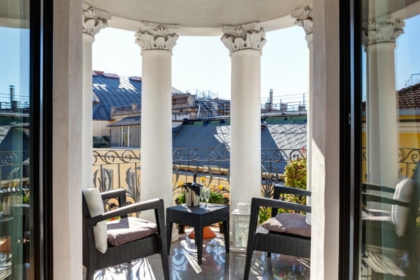 Dharma Luxury Hotel - Looking out to a terrace with columns and a view of buildings opposite.