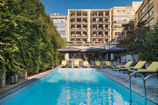 H10 Metropolitan - a pool with chairs and trees in front of a building