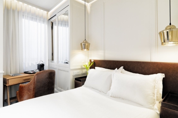 H10 Montcada Boutique Hotel - a bed with white sheets and brown headboard