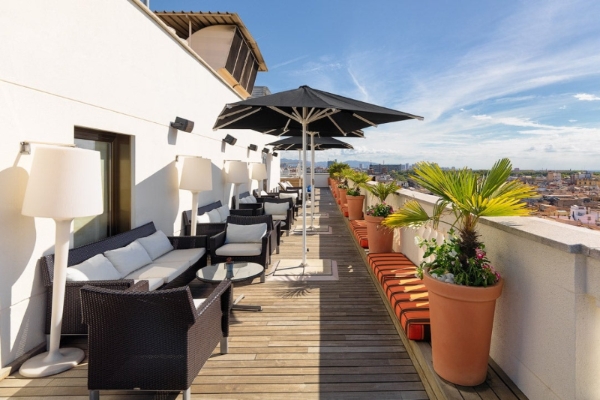 H10 Montcada Boutique Hotel - a patio with chairs and umbrellas on a deck