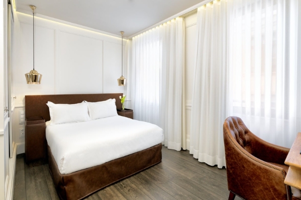 H10 Montcada Boutique Hotel - a room with a bed and a leather chair