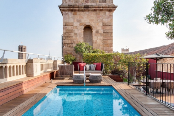 Hotel 1898 - a pool with a wood deck and a stone tower