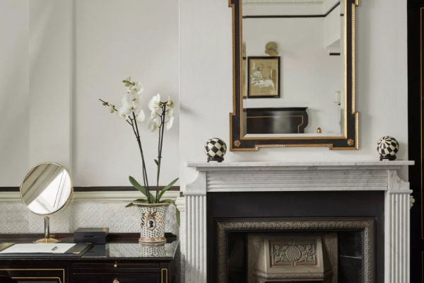 Hotel 41 - a fireplace with a mirror and a vase of flowers