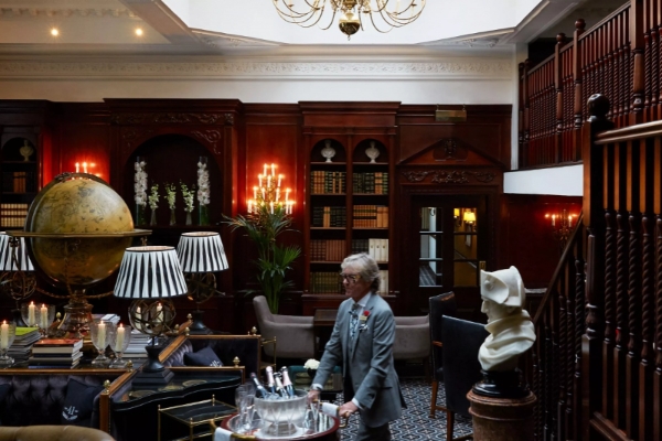 Hotel 41 - a man in a suit standing in a room with a table and chairs