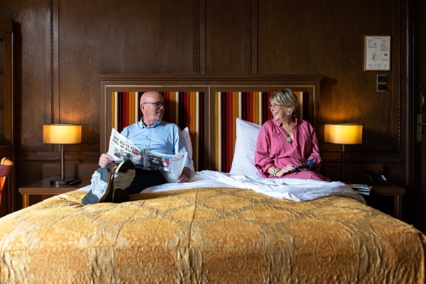 Hotel Aalders - a man and woman sitting on a bed