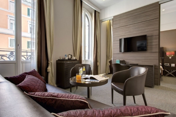 Hotel Artemide - Hotel room with plush furnishings and wall mounted television.