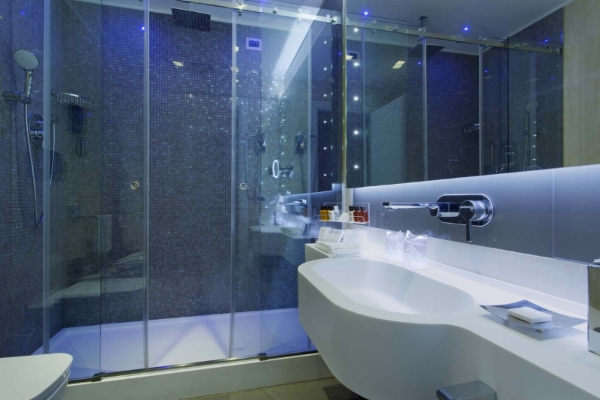 Hotel Artemide - Spacious shower with glass doors and mosaic tiles.