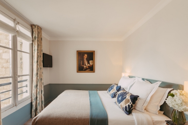 Hotel d'Orsay - Esprit de France - a bed with pillows and a painting on the wall