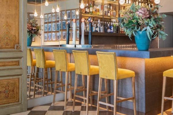 Hotel Duquesa de Cardona - a bar with yellow chairs and a mirror