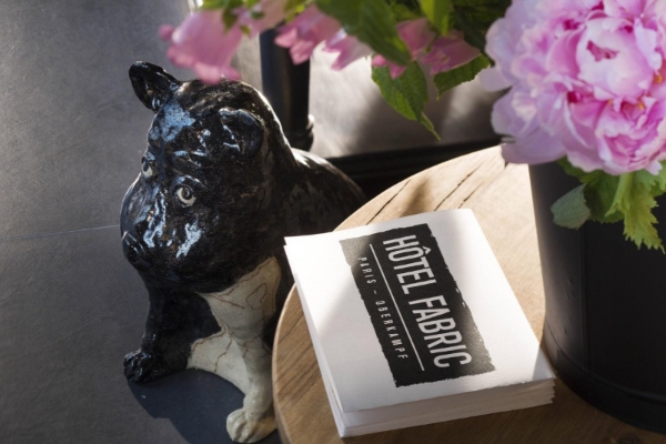 Hotel Fabric - a black and white dog statue next to a stack of white papers