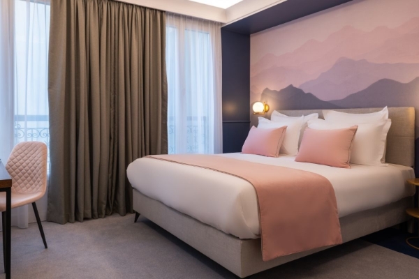 Hotel Le Milie Rose - a bed with pink pillows and a wall with a painting behind it